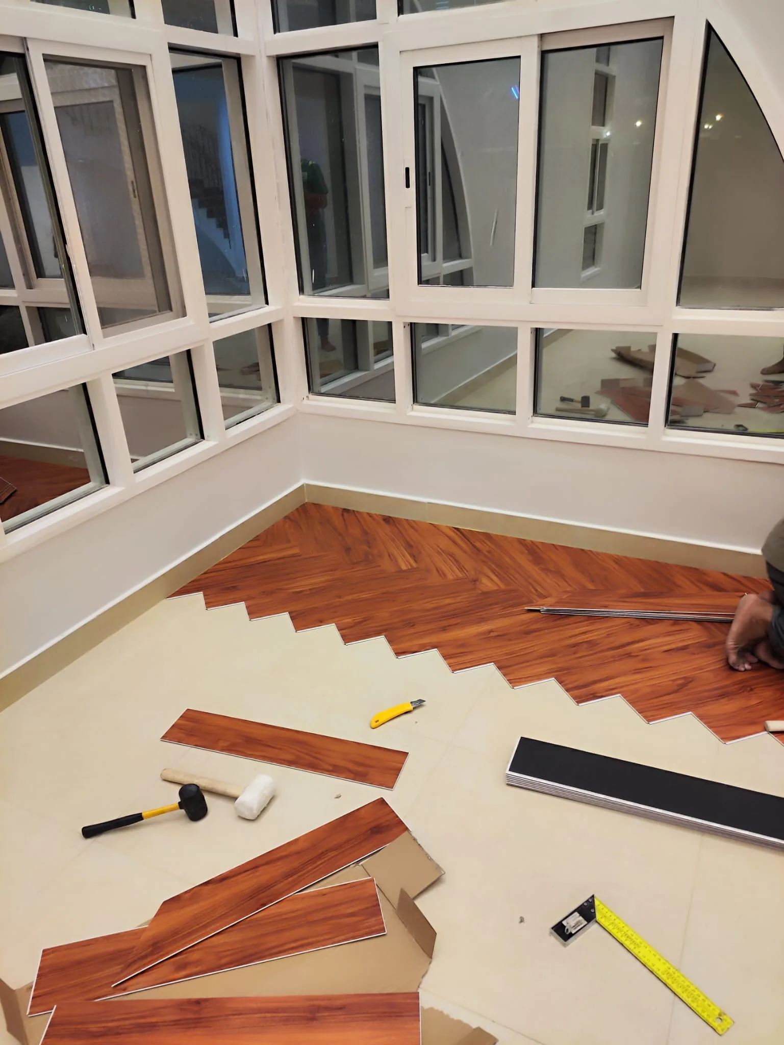 Herringbone laminate flooring being laid plank by plank over a levelled sub-floor in Qatar