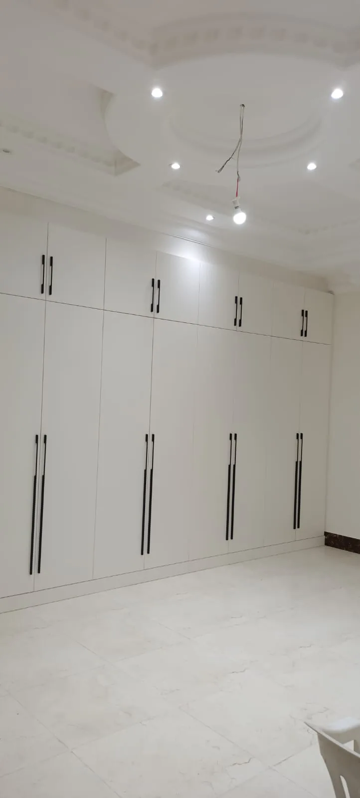 White fitted wardrobes with long black handles running the width of a bedroom
