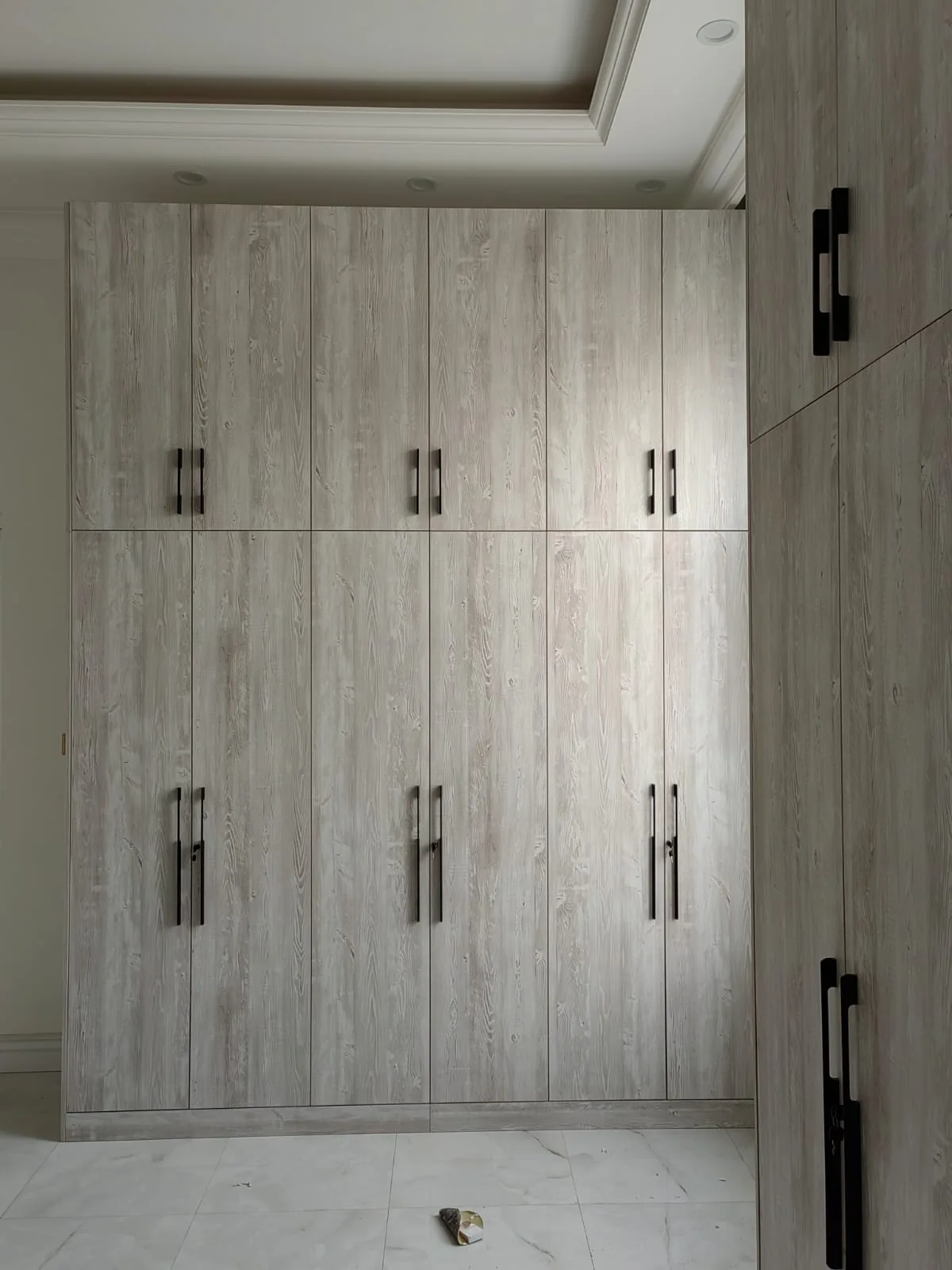 Fitted wardrobes in a grey wood finish with black handles