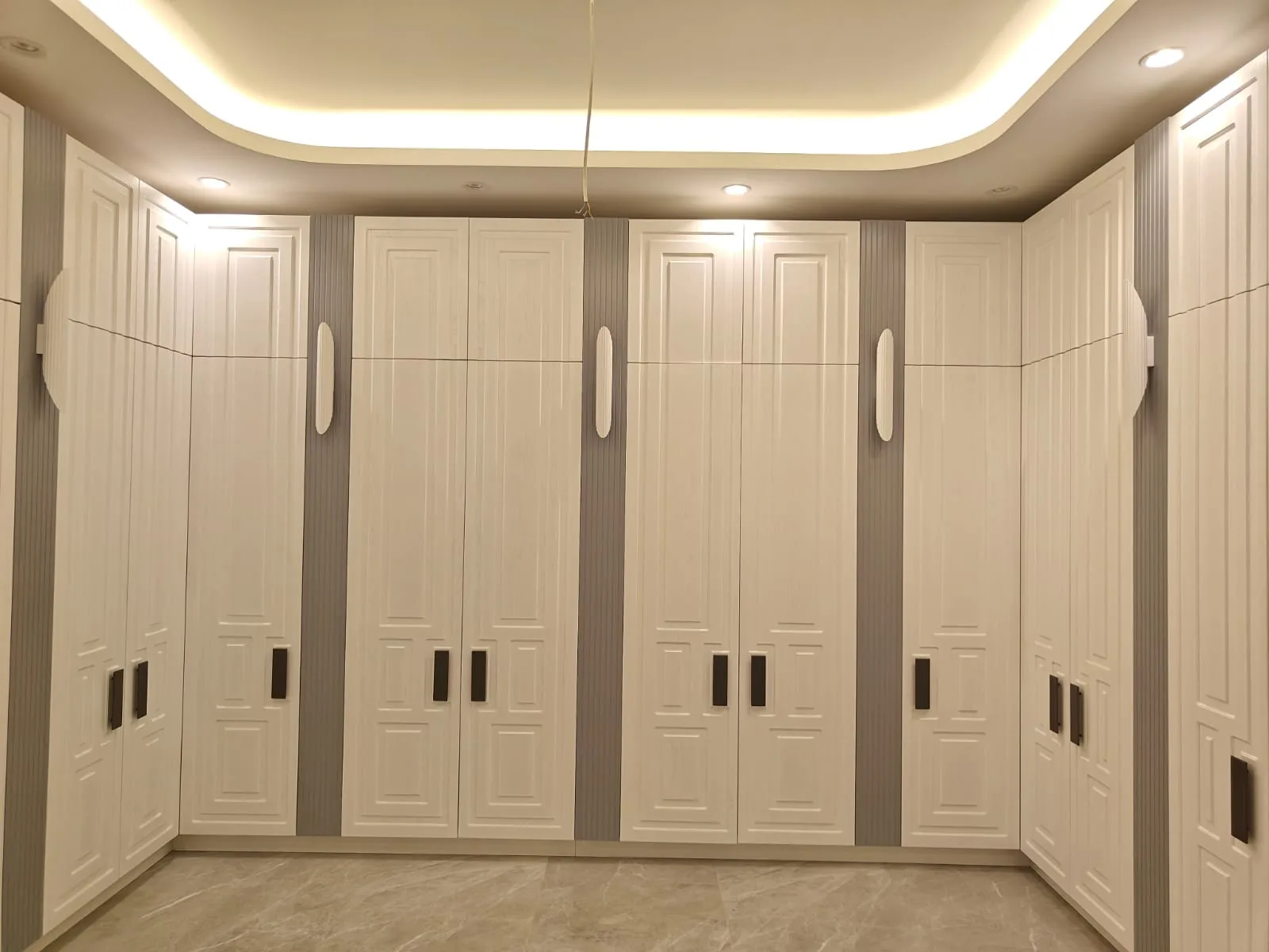 Floor-to-ceiling fitted wardrobes with panelled doors in a Qatari dressing room