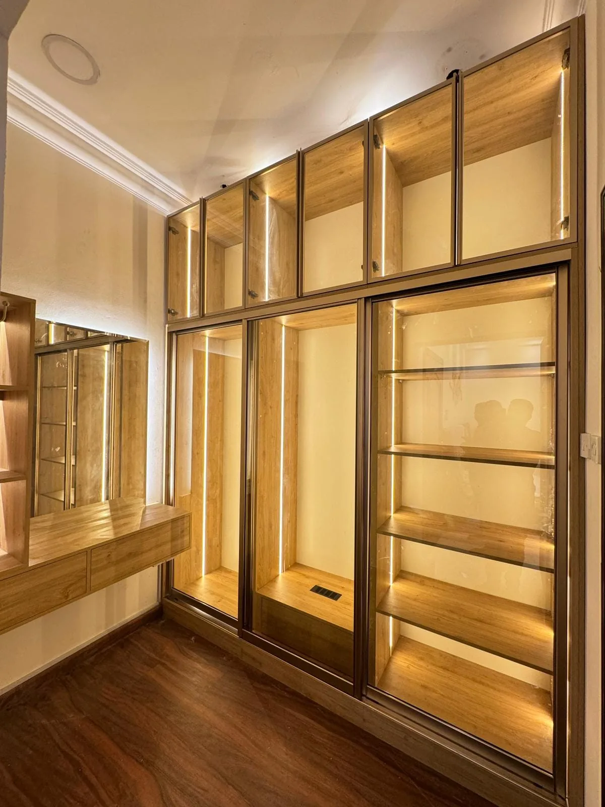 Walk-in wardrobe interior with glass shelving and integrated LED lighting